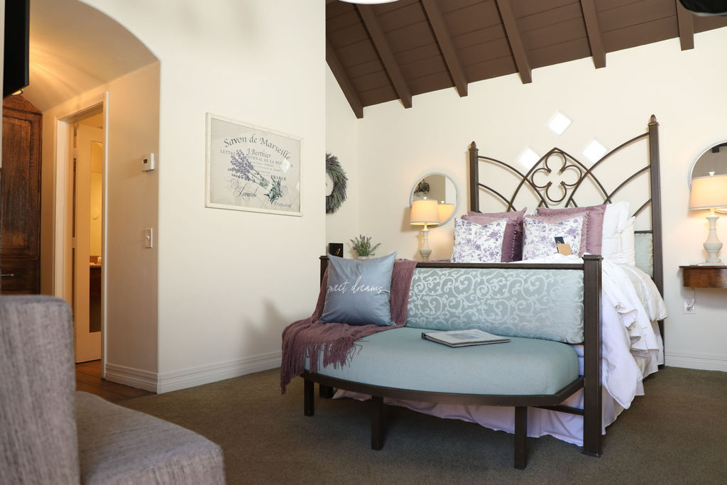 A wide view of a room with a bed, chaise longue, and vaulted ceiling.