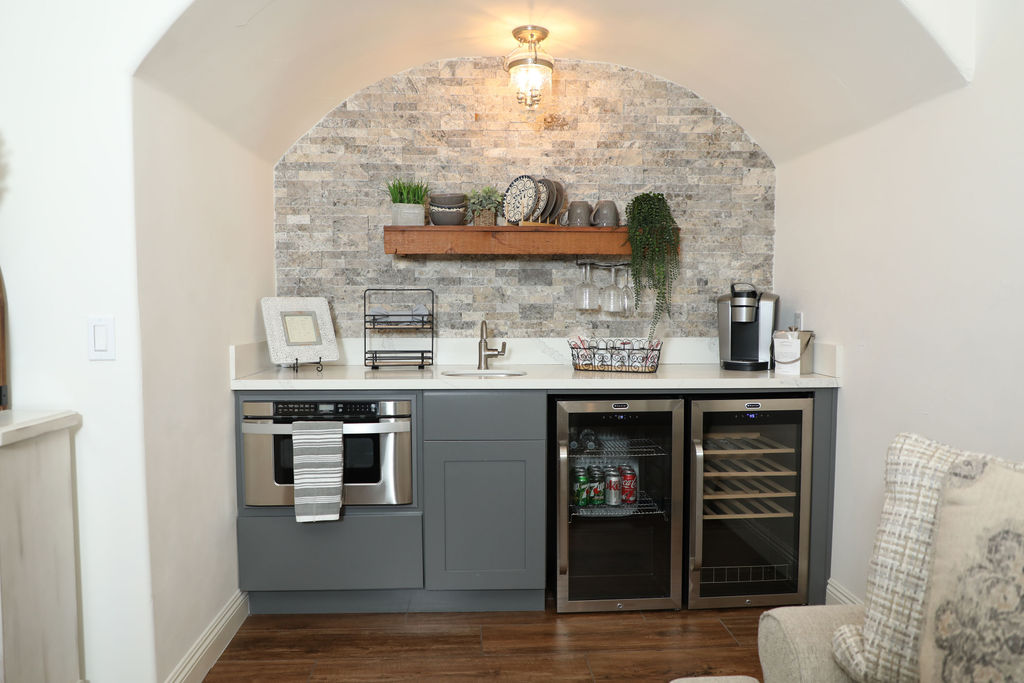 A wet bar with a wine fridge, mini fridge, coffee maker, and dishwasher
